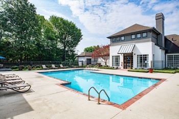 A swimming pool with lounge chairs and a building in the background
